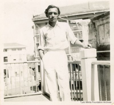 **Young Tyeb Mehta, c. 1940s**
A full length shot of Tyeb Mehta, dressed in a shirt and trousers, standing on a terrace, his hands resting on a pillar.